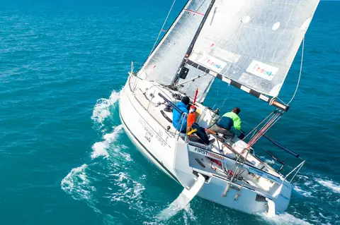Velero navegando de ceñida en mar abierto, vista desde dron